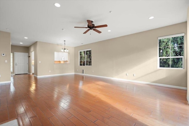 spare room with hardwood / wood-style floors and ceiling fan with notable chandelier