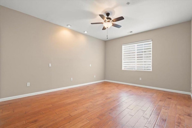 empty room with ceiling fan and light hardwood / wood-style flooring