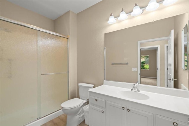 bathroom with hardwood / wood-style floors, vanity, toilet, and a shower with shower door