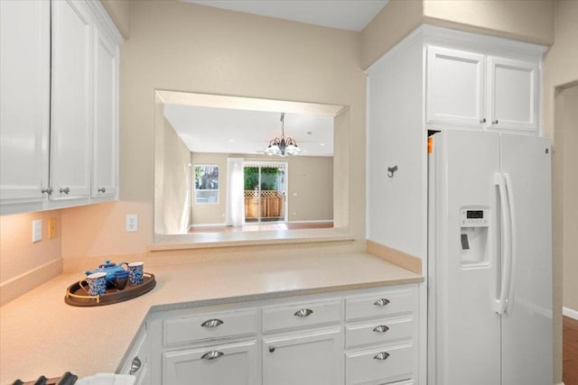 kitchen featuring white cabinets, white fridge with ice dispenser, and an inviting chandelier