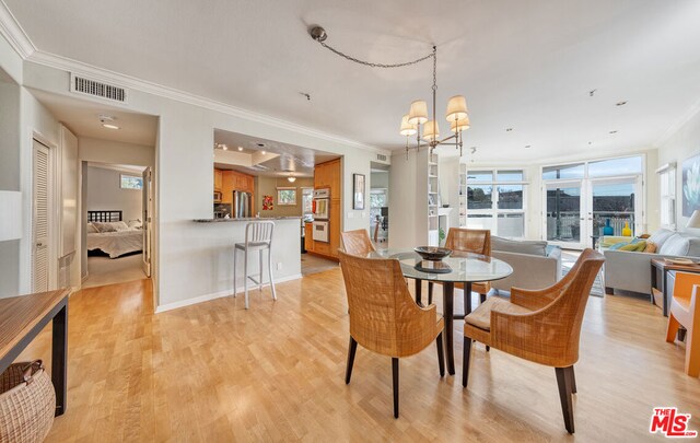 dining room with crown molding, a notable chandelier, and light hardwood / wood-style flooring