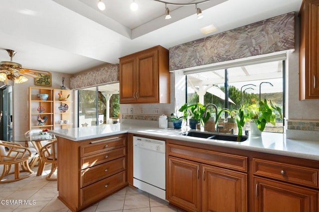 kitchen with kitchen peninsula, ceiling fan, a raised ceiling, white dishwasher, and sink