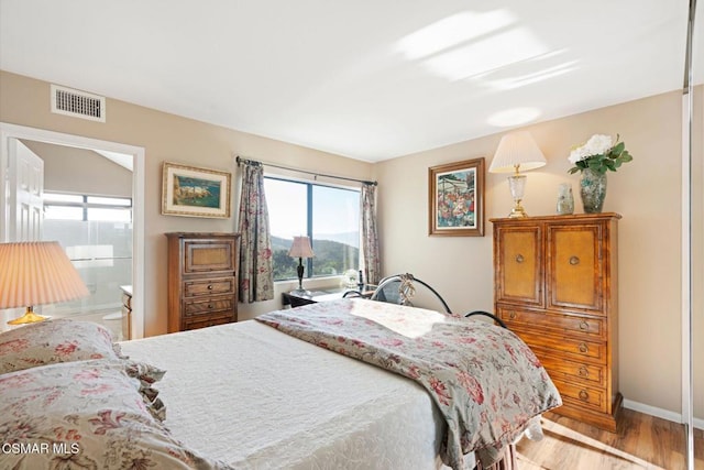 bedroom featuring ensuite bathroom and light hardwood / wood-style flooring