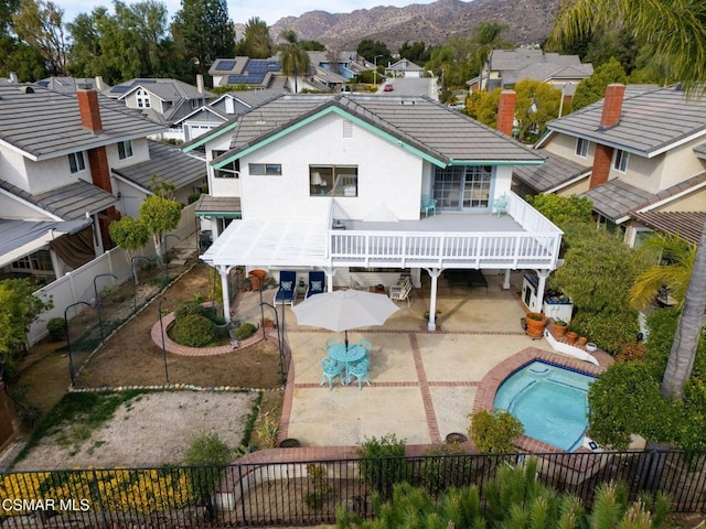 rear view of property with a fenced in pool, a mountain view, and a patio