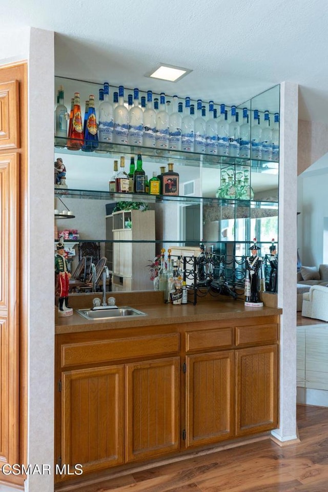 bar featuring a textured ceiling, hardwood / wood-style flooring, and sink