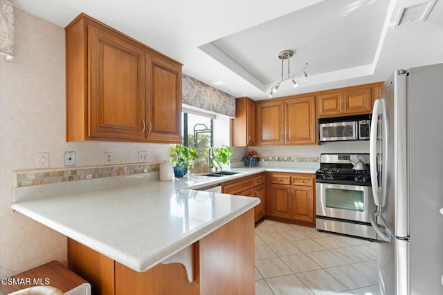 kitchen featuring appliances with stainless steel finishes, sink, kitchen peninsula, a tray ceiling, and a breakfast bar area