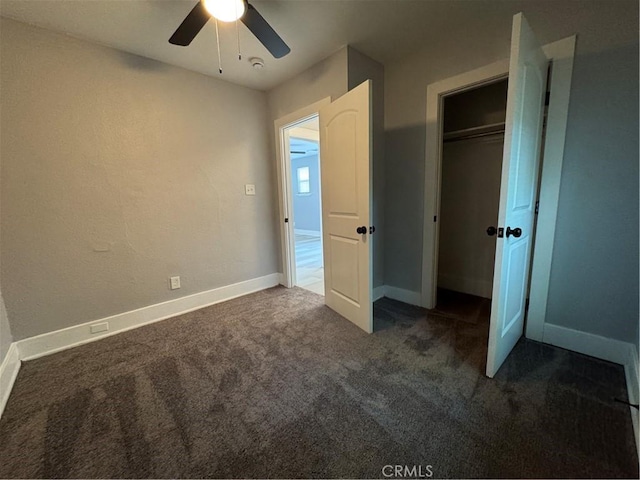 unfurnished bedroom with ceiling fan, dark carpet, and a closet