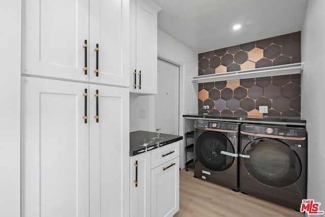 laundry room featuring cabinets, independent washer and dryer, and light hardwood / wood-style flooring