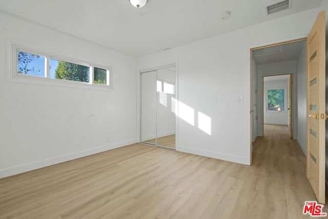 unfurnished bedroom with a closet and light hardwood / wood-style floors