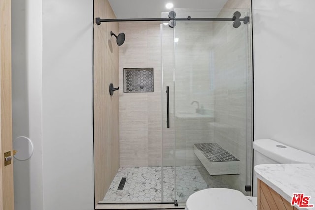 bathroom featuring a shower with shower door, toilet, and vanity