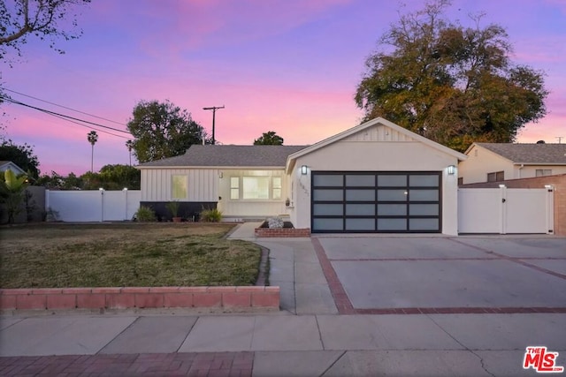 ranch-style home featuring a garage and a yard