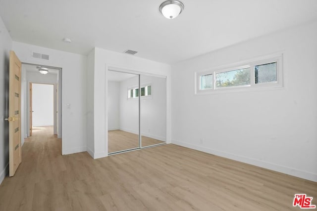 unfurnished bedroom featuring a closet and light hardwood / wood-style floors