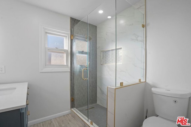 bathroom with toilet, vanity, a shower with door, and hardwood / wood-style floors