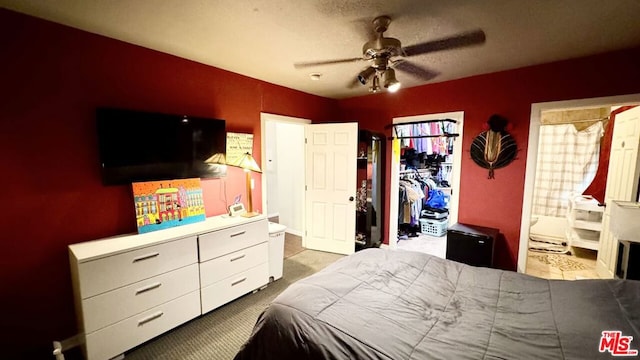 carpeted bedroom featuring ceiling fan, ensuite bath, a textured ceiling, and a closet