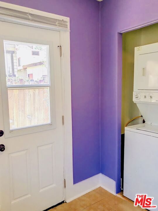 laundry area with stacked washer and dryer and tile patterned floors