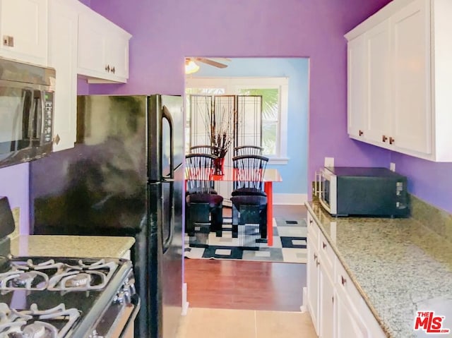 kitchen featuring ceiling fan, white cabinets, gas range oven, and light stone counters