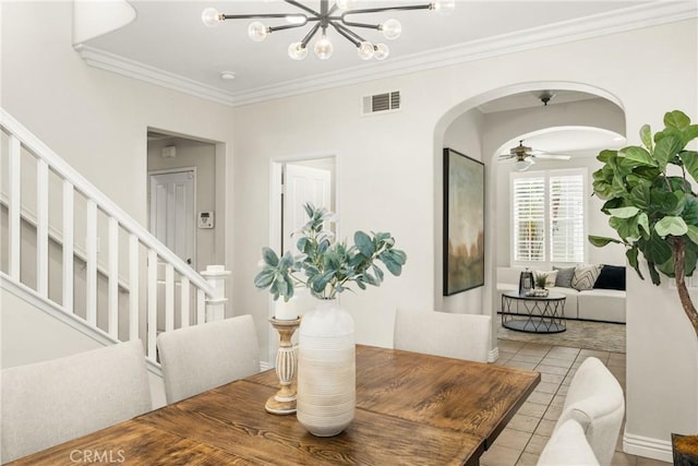 dining space with ceiling fan with notable chandelier, tile patterned floors, and crown molding