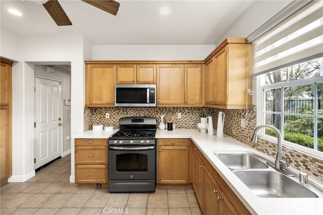 kitchen featuring appliances with stainless steel finishes, sink, backsplash, light tile patterned flooring, and ceiling fan