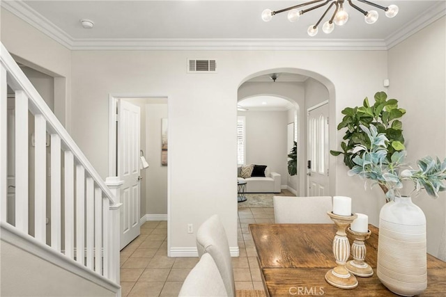 dining space with light tile patterned floors, ornamental molding, and an inviting chandelier