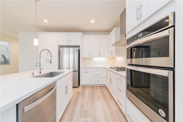 kitchen featuring decorative light fixtures, sink, stainless steel appliances, and white cabinetry