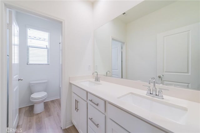 bathroom with toilet, vanity, and hardwood / wood-style flooring