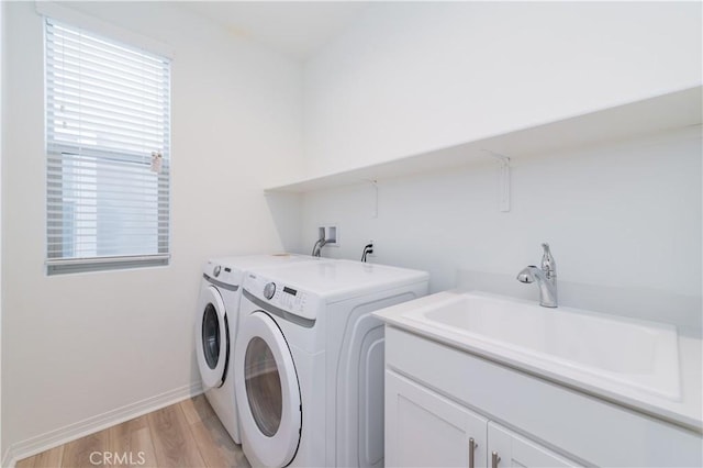 laundry area featuring light wood-type flooring, sink, washer and dryer, and cabinets