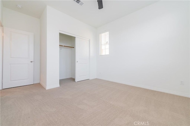 unfurnished bedroom featuring ceiling fan, light colored carpet, and a closet