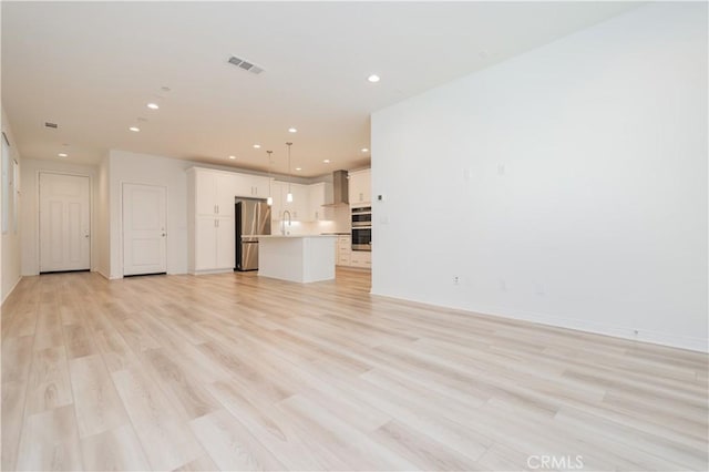 unfurnished living room featuring light hardwood / wood-style flooring and sink