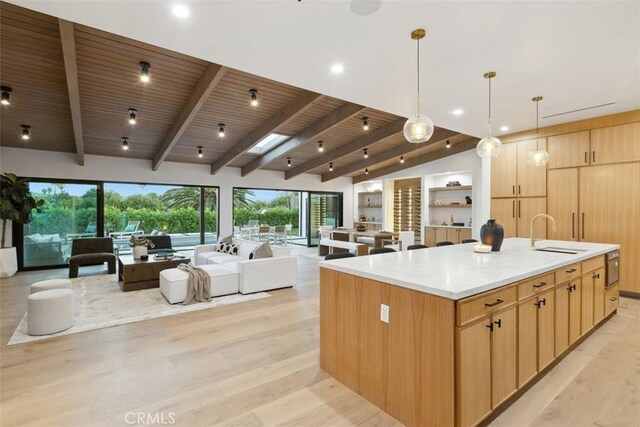 kitchen with hanging light fixtures, light brown cabinetry, a large island, and sink