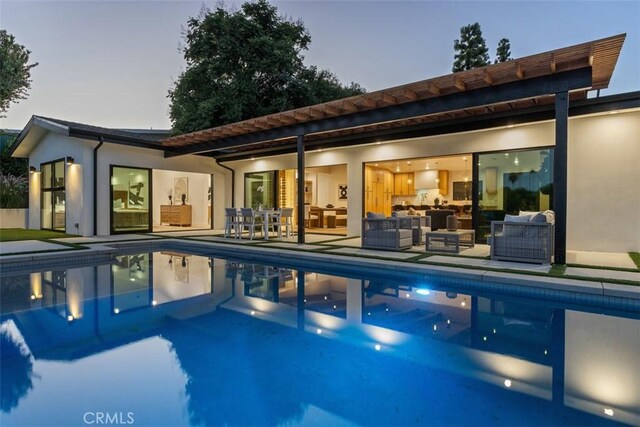 pool at dusk featuring an outdoor living space and a patio area