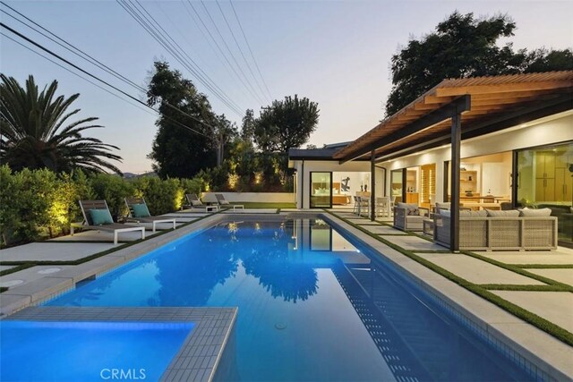 pool at dusk with an outdoor hangout area and a patio area