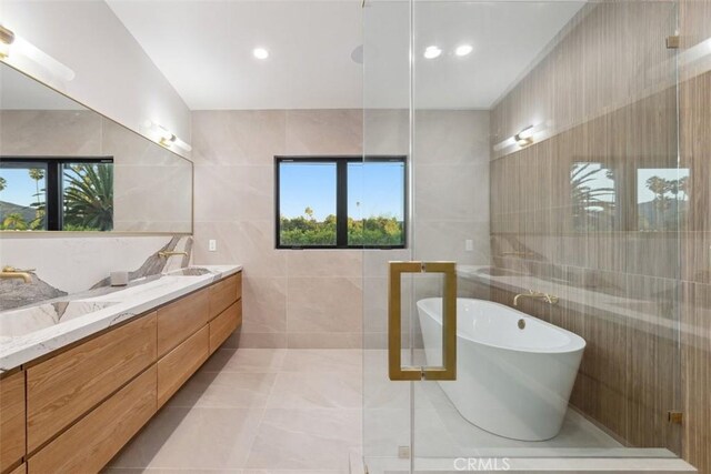 bathroom featuring a bathing tub, tile walls, and vanity