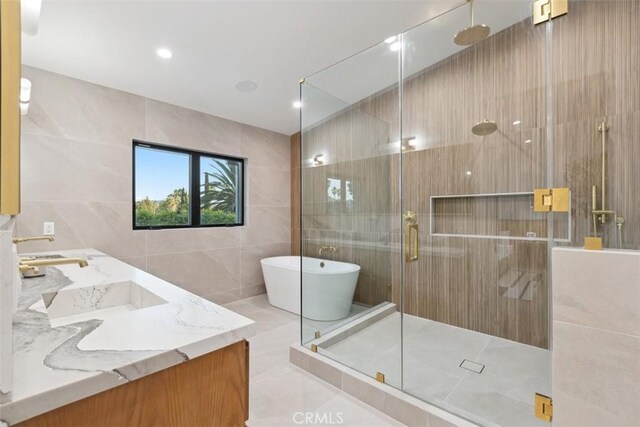 bathroom featuring tile patterned flooring, vanity, tile walls, and independent shower and bath