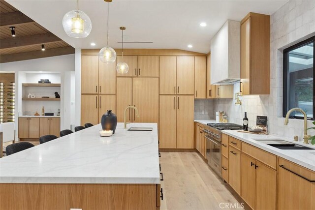 kitchen with a kitchen island, sink, vaulted ceiling with beams, and wall chimney range hood