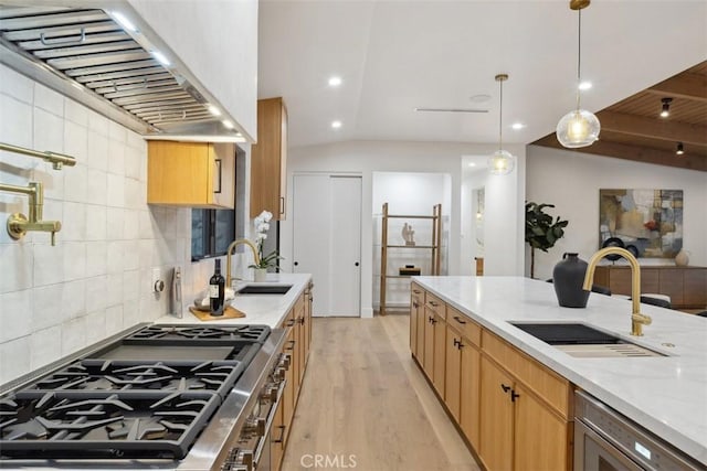 kitchen featuring tasteful backsplash, lofted ceiling, wall chimney range hood, light stone counters, and sink