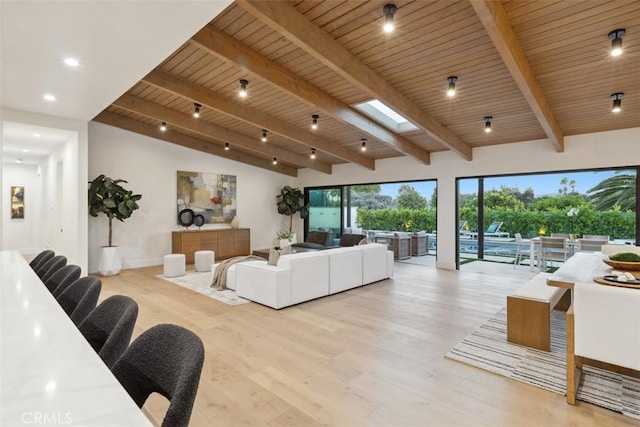 living room with light hardwood / wood-style floors, vaulted ceiling with skylight, and wood ceiling