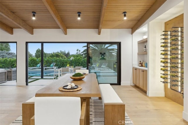 dining room featuring beamed ceiling, light hardwood / wood-style floors, and wooden ceiling