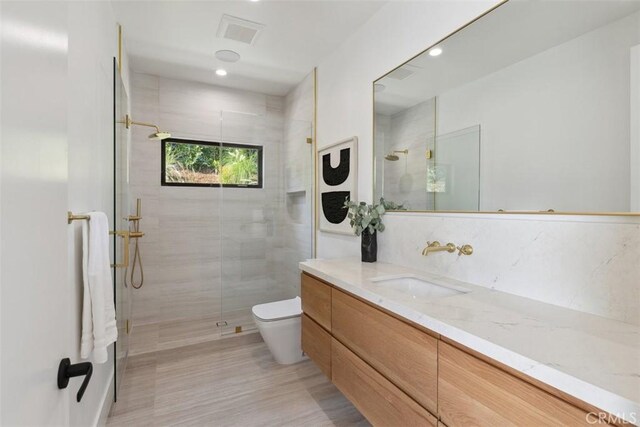 bathroom featuring a shower with shower door, toilet, and vanity