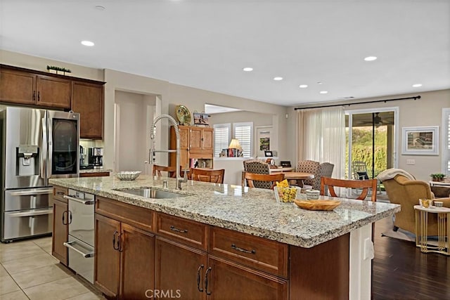 kitchen with stainless steel fridge, sink, a center island with sink, and a wealth of natural light