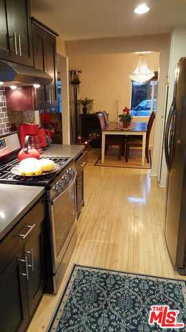 kitchen with backsplash, dark brown cabinetry, light hardwood / wood-style flooring, and stainless steel appliances