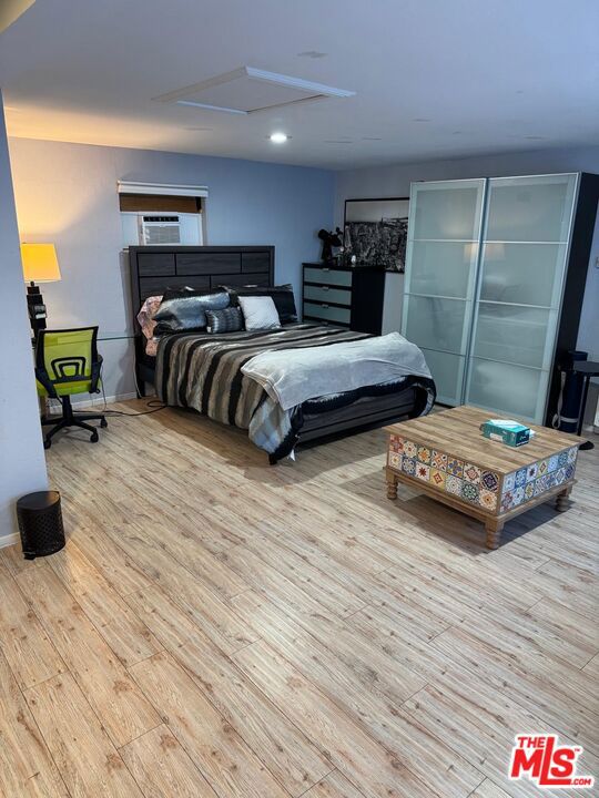 bedroom with cooling unit and light hardwood / wood-style flooring