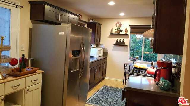 kitchen featuring light wood-type flooring, cream cabinetry, stainless steel refrigerator with ice dispenser, and dark brown cabinets