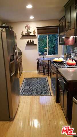 kitchen with light wood-type flooring, appliances with stainless steel finishes, and dark brown cabinets