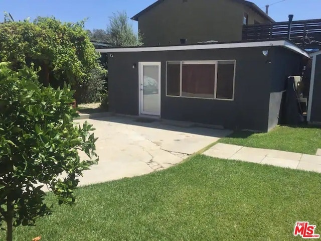 back of property with a lawn and a patio