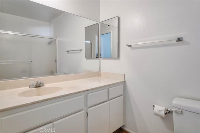 bathroom with toilet, vanity, and walk in shower