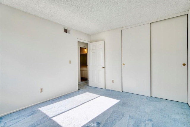 unfurnished bedroom featuring light colored carpet, a textured ceiling, and a closet