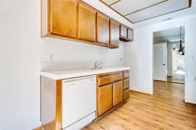 kitchen featuring light wood-type flooring, dishwasher, tile countertops, and a chandelier