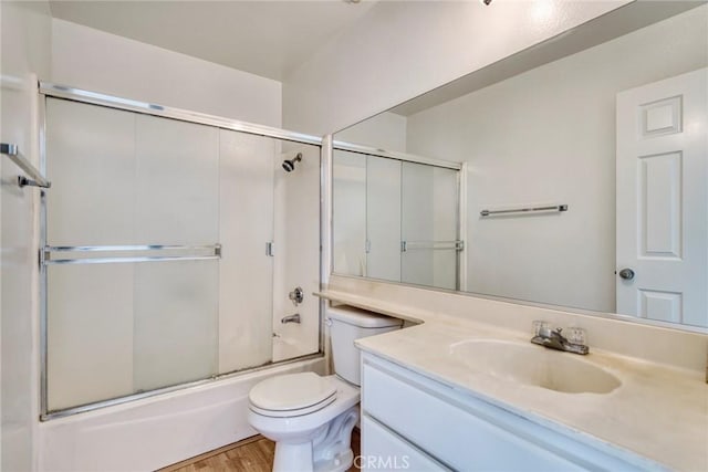 full bathroom featuring toilet, enclosed tub / shower combo, vanity, and hardwood / wood-style floors