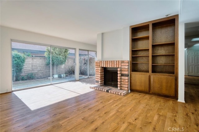 unfurnished living room with a brick fireplace and light hardwood / wood-style flooring