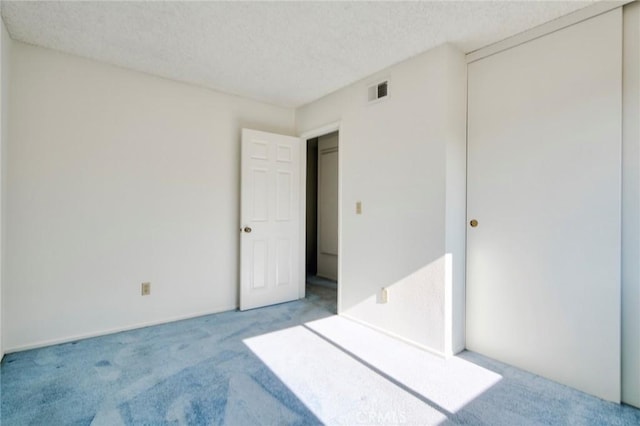 unfurnished bedroom with carpet, a closet, and a textured ceiling